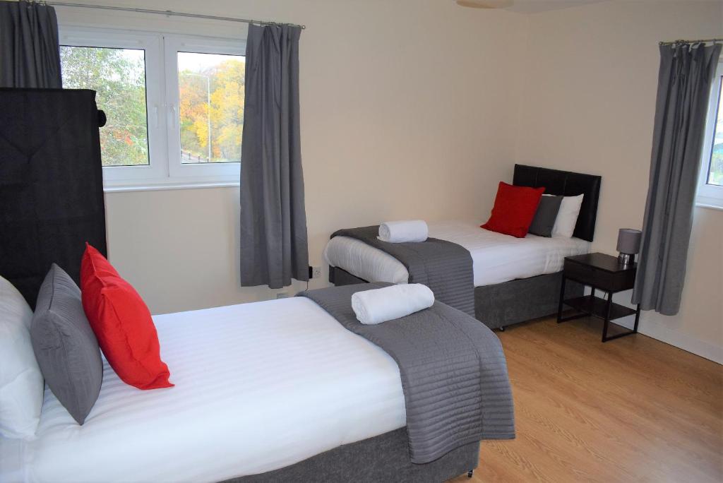 利文斯顿Kelpies Serviced Apartments Callum- 3 Bedrooms- Sleeps 6的客房配有两张带红白色枕头的床。