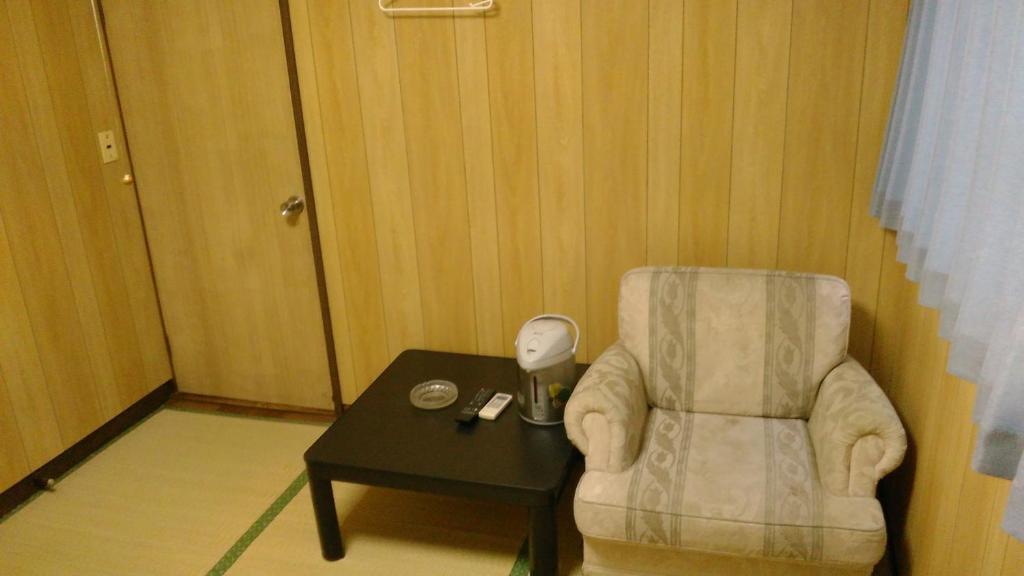 Maisaka高梁卡施布奈藤传统日式民宿的一间带椅子和一张桌子及台灯的房间
