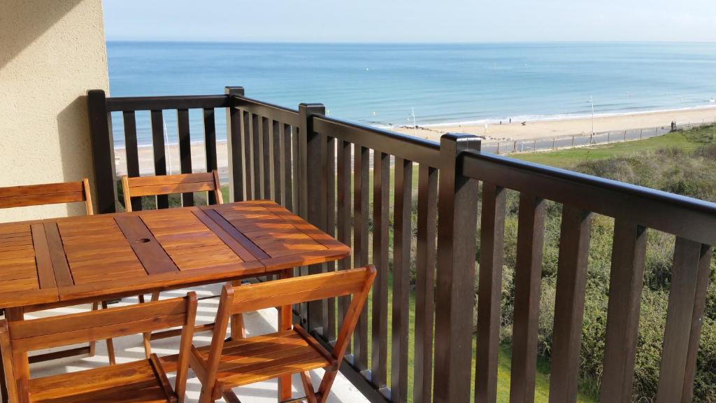 卡布尔Magnifique vue Mer et Forêt的海滩阳台的木桌和椅子