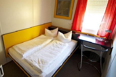 代特尔巴赫佩利坎汽车旅馆的一间卧室配有一张床和一张桌子及椅子
