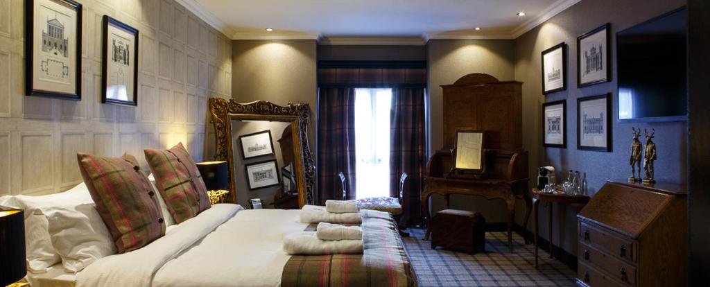 邓弗姆林福勒斯特公园度假酒店的一间卧室配有一张大床和镜子