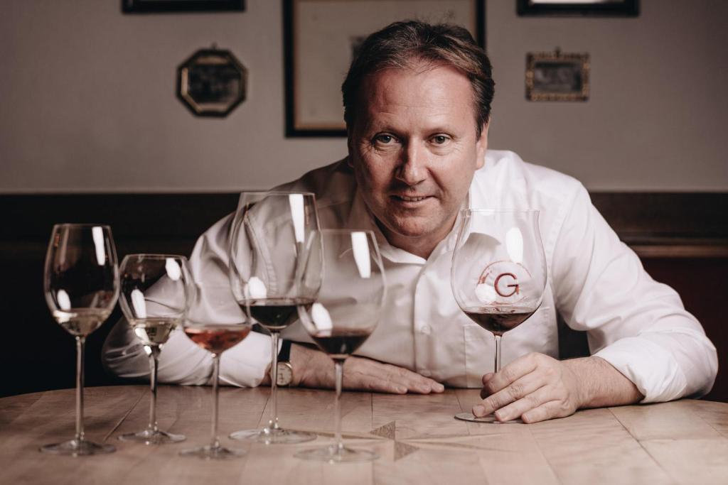 瑟尔DER GREIL - Wein & Gourmethotel的坐在桌子上拿着四杯酒的人