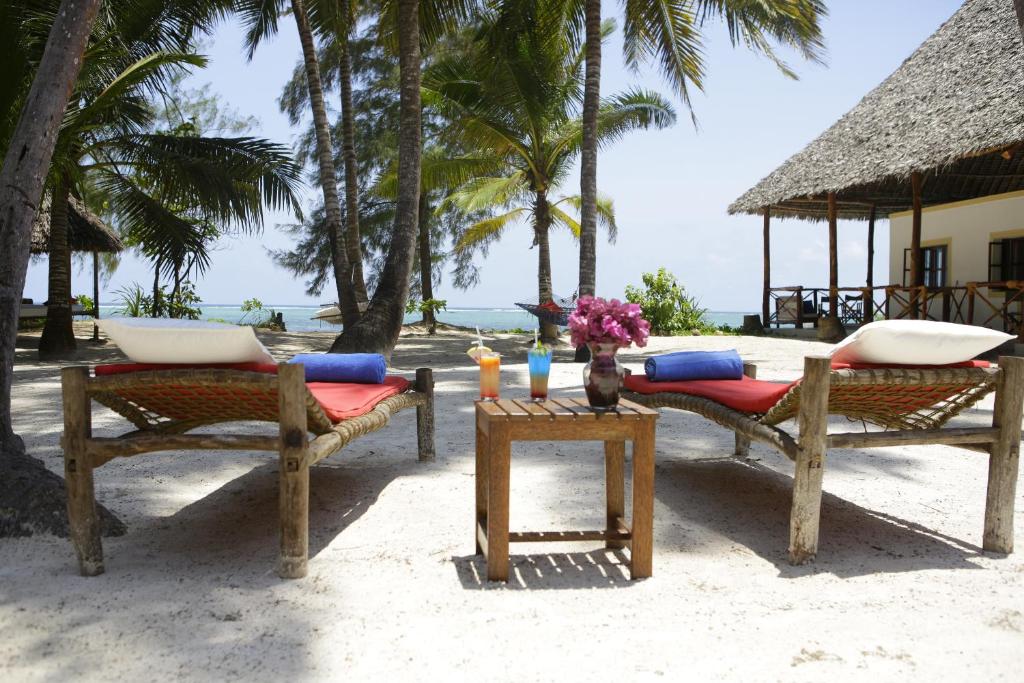 马特姆维Panga Chumvi Beach Resort的海滩上的两把椅子和一张桌子