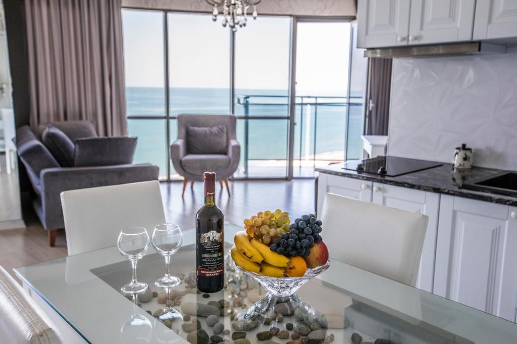 巴统Tina's Apartments with Panoramic Sea view的一瓶葡萄酒和一碗水果放在桌子上