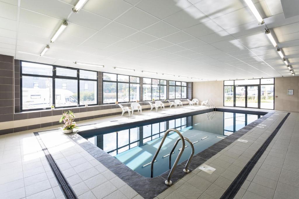 梅里尼亚克Nemea Appart Hotel Stadium Bordeaux aéroport的一个带椅子的游泳池,位于带窗户的大房间