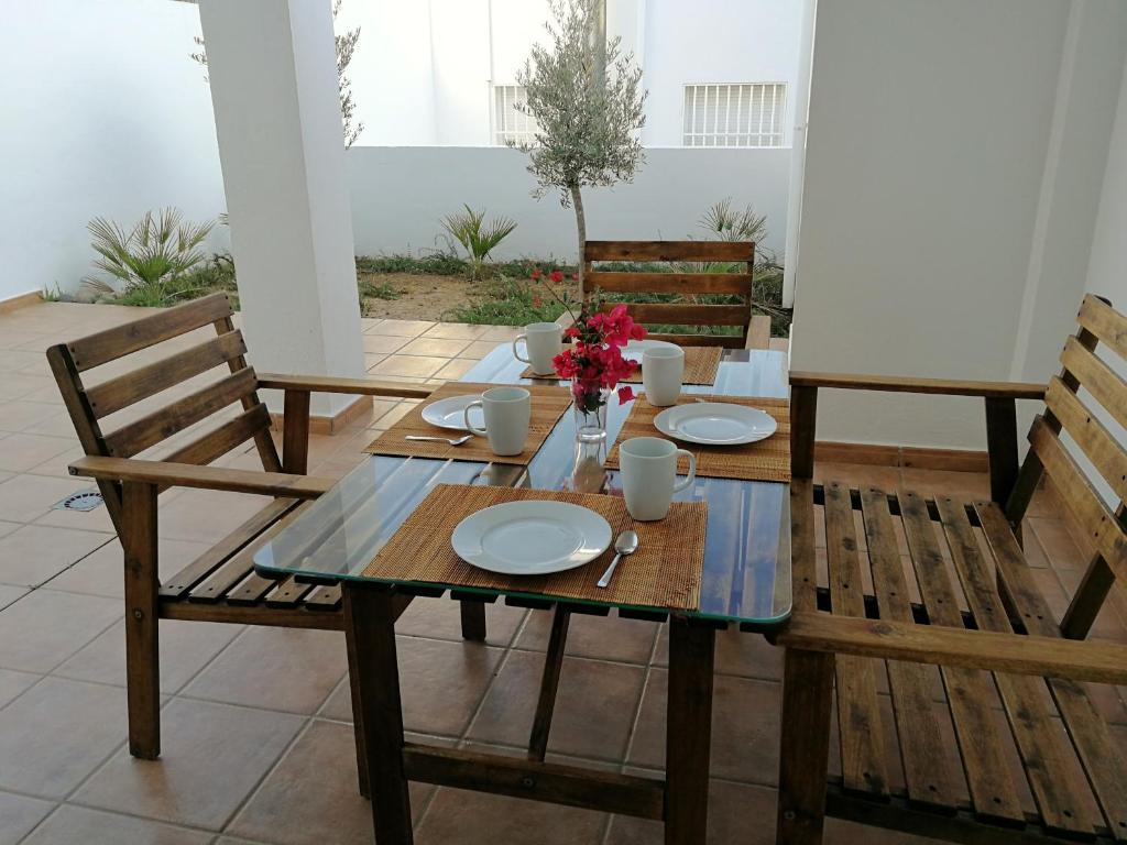 拉斯内格拉斯Apartamento Los Olivos的一张木桌和椅子,上面有盘子和鲜花
