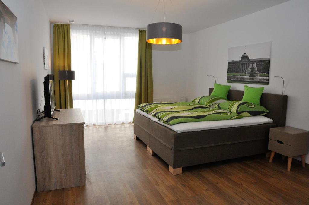 威斯巴登奎林公寓的一间卧室配有一张带绿色枕头的床和电视。