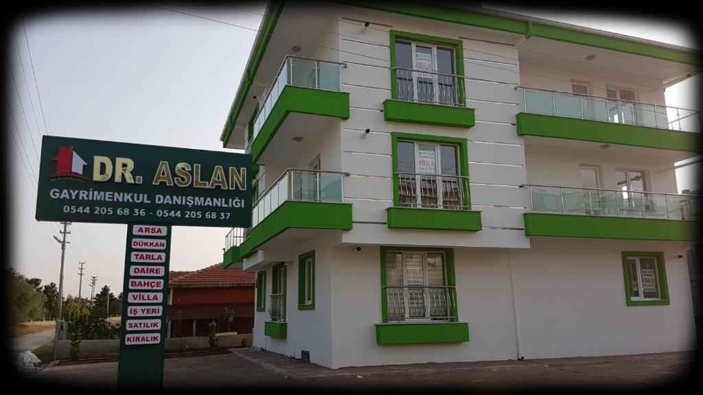 EsenbogaDr Aslan Apart Hotel的一座带绿色阳台的建筑,前面有一个标志