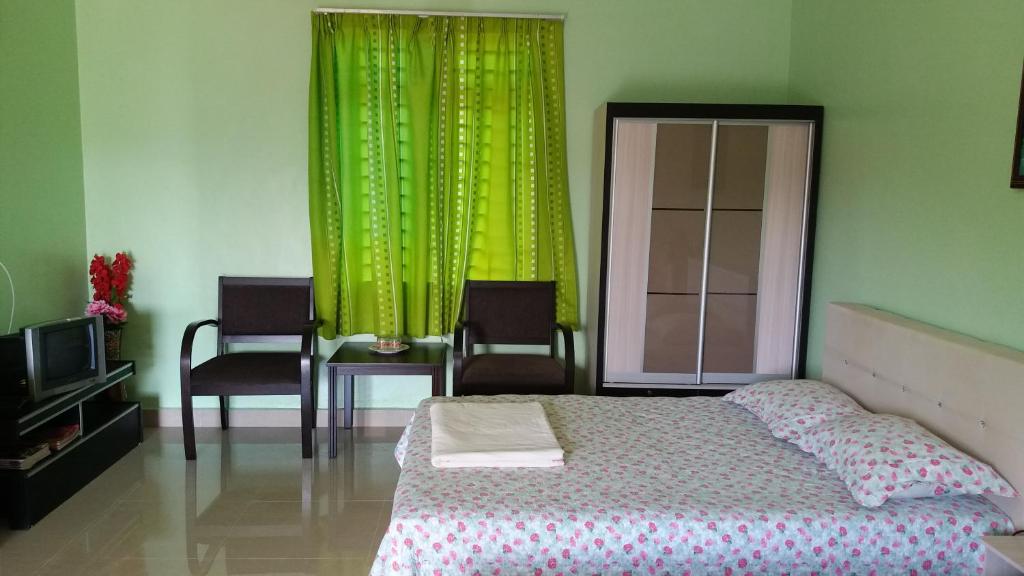 Paya Rewak达雅因迪娜民宿的一间卧室配有床和绿帘