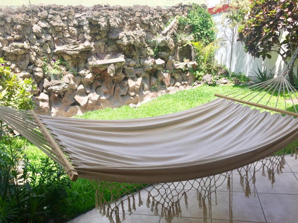 利马Lima Mini Aparts Monterrico - Cerca Embajada EEUU的一个带石墙的花园内的吊床