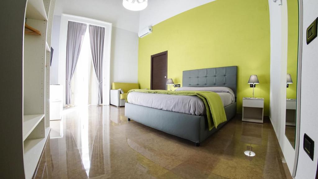 那不勒斯贝维雷洛套房旅馆的一间卧室设有一张床和黄色的墙壁