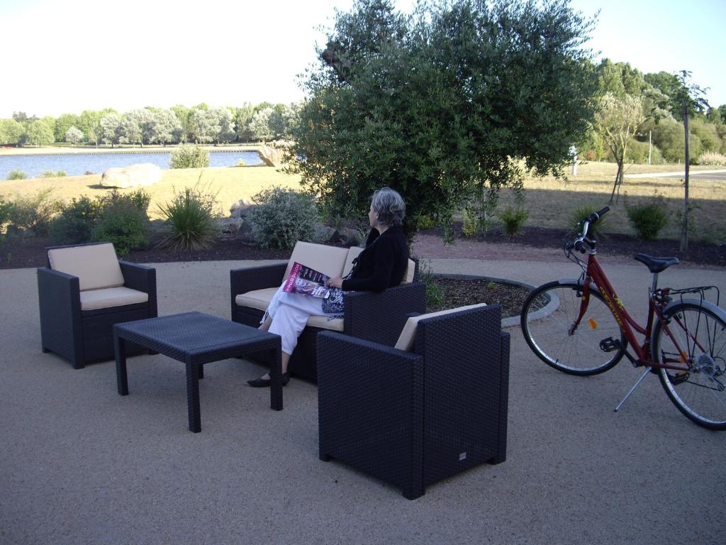 Mansigné拉铁勒斯奥立威酒店的坐在椅子上的女人,在自行车旁边用笔记本电脑