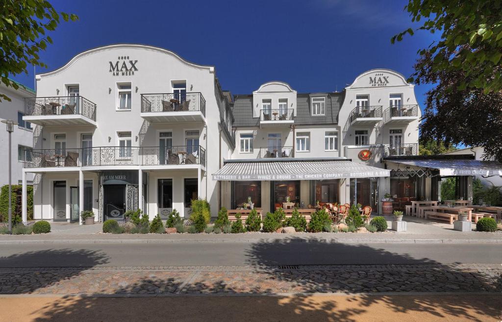 奥斯赛拜-屈隆斯博恩库伦斯伯恩最大海滩酒店的一座白色的大建筑,前面设有桌椅