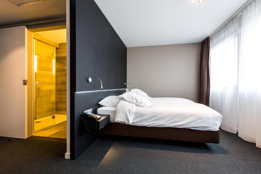 阿尔斯特Tower Hotel Aalst的一间卧室设有一张床和一个步入式淋浴间。