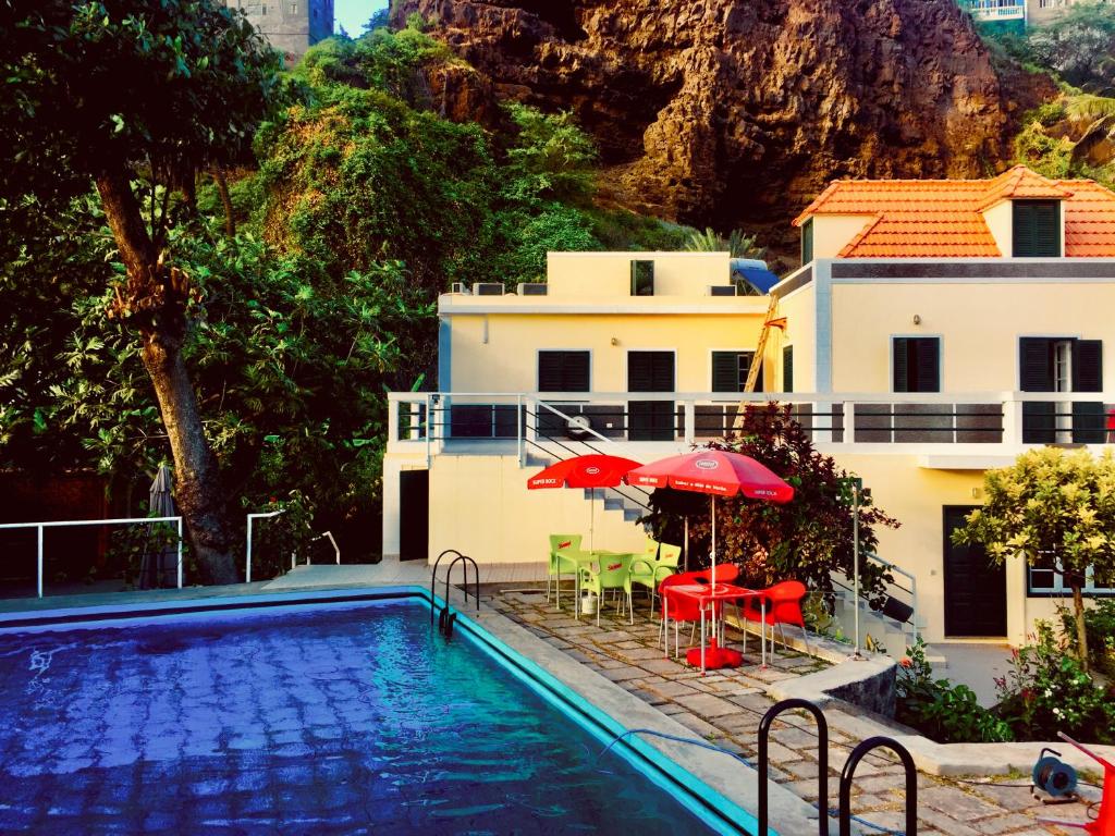 Ribeira GrandeCasa Santa Barbara Deluxe的房屋旁的游泳池配有椅子和遮阳伞