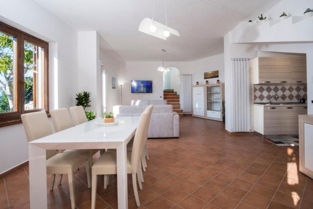 马萨鲁布朗斯Villa d'aMare Capri View的用餐室以及带白色桌椅的起居室。