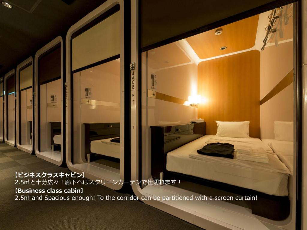 长崎长崎领衔胶囊旅馆的小房间设有一张床和镜子