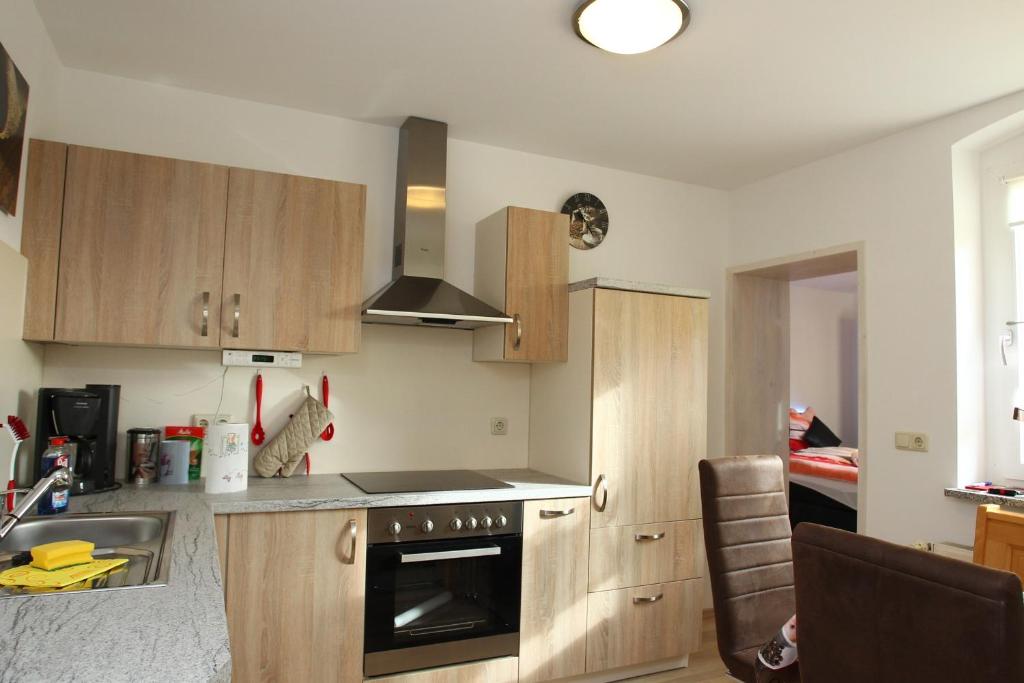 格赖茨Ferienwohnung Kopp II的厨房配有木制橱柜和炉灶烤箱。