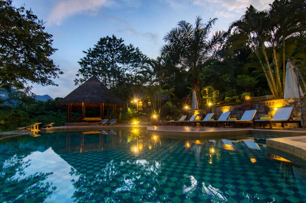 琅勃拉邦山林自然生活方式酒店的夜间带椅子和凉亭的游泳池