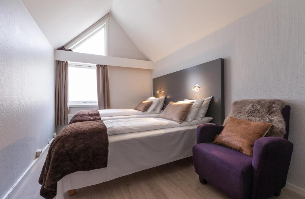 特罗姆瑟恩特维京酒店的一间卧室配有一张大床和一张紫色椅子