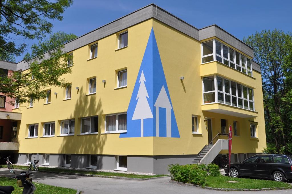 萨尔茨堡爱德华海因里希屋旅舍的一座黄色的建筑,上面涂有蓝色的箭头