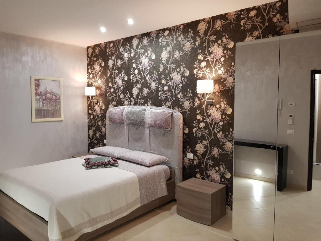 圣塞韦罗Le Cale' B&B的一间卧室配有一张床和一张带花卉壁纸的墙壁