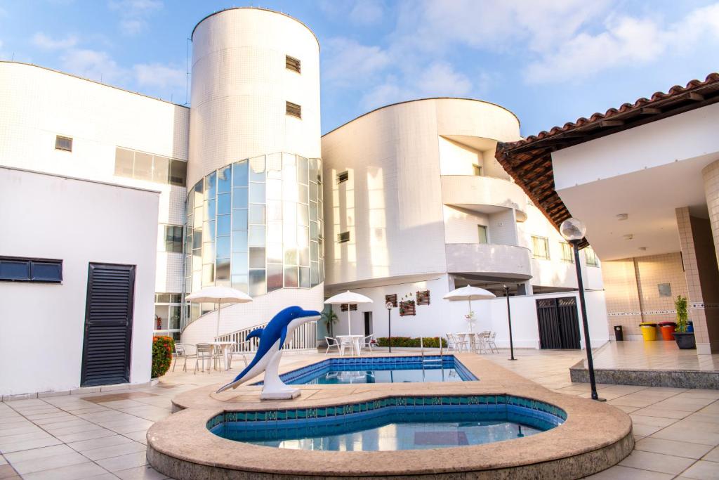 圣路易斯Costa Atlantico Hotel的一座带海豚雕像的建筑的庭院内的游泳池