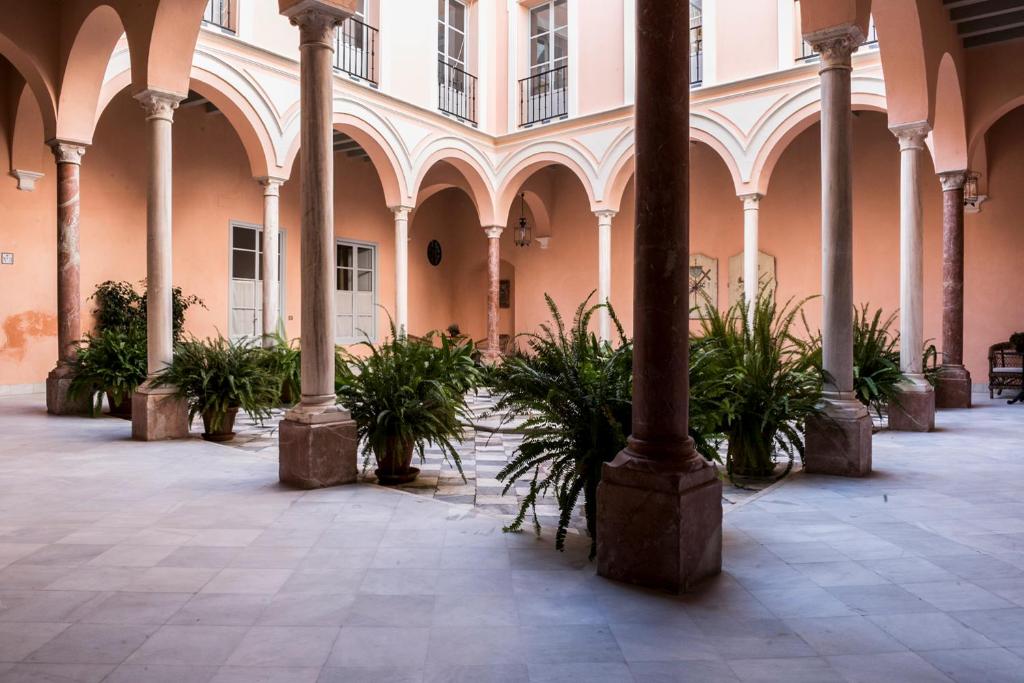 塞维利亚帕拉克玛尔姆乐斯公寓式酒店的庭院中带有柱子和盆栽植物的建筑