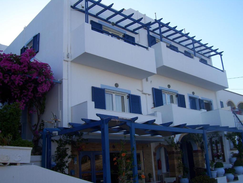 阿齐亚·佩拉加·基西拉佩拉吉亚海滩一室公寓酒店的白色的建筑,有蓝色百叶窗和遮阳篷