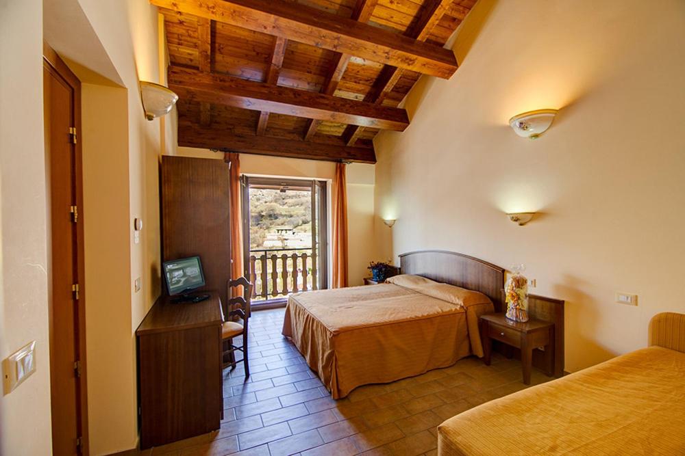 CasamainaGinepro d'Abruzzo的一间卧室设有两张床、一台电视和一扇窗户。