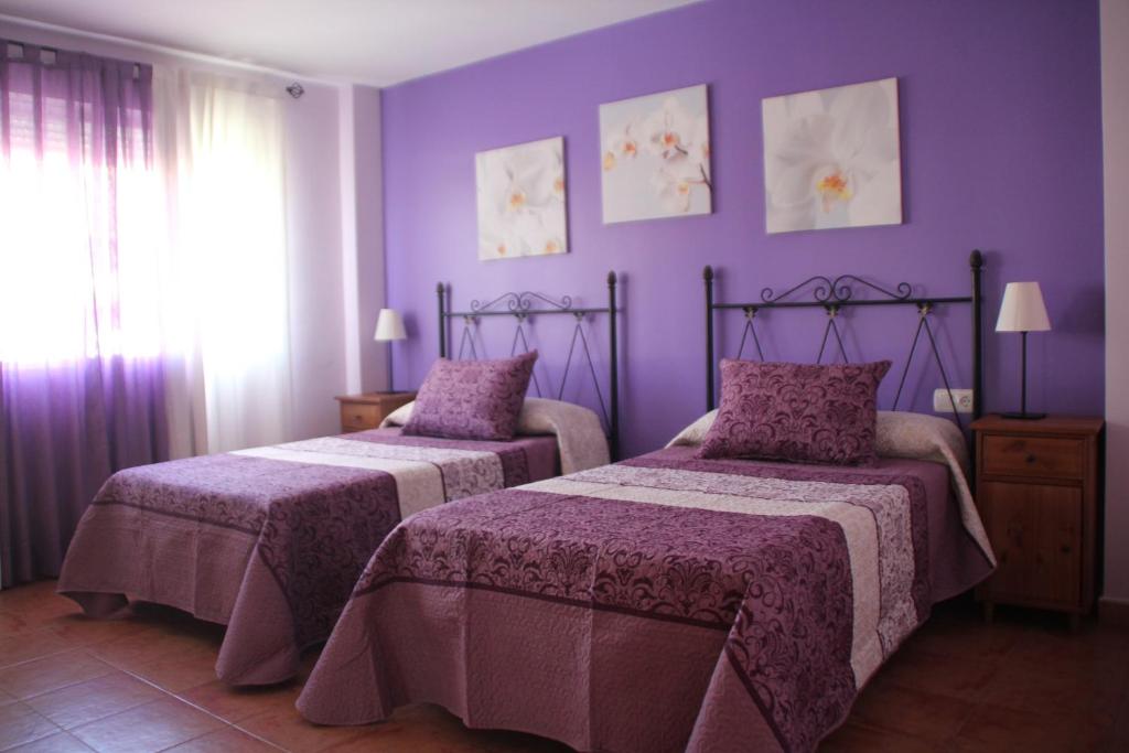 TalaveruelaHostal Zaguan的紫色墙壁客房的两张床