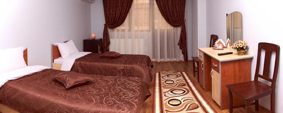 加拉茨Hotel Corneliuss的一间卧室配有两张床、一张桌子和一把椅子