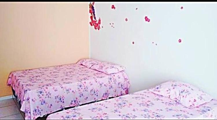 库亚巴Pousada CPA的卧室内的两张床,配有粉红色的床单