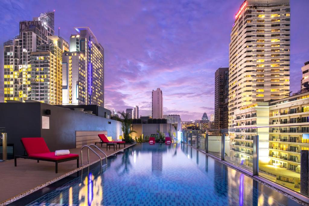 曼谷Travelodge Sukhumvit 11的一个带椅子的屋顶游泳池和城市天际线