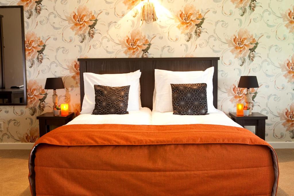 德吕嫩德赖斯酒店的一间卧室配有一张带橙色毯子和枕头的大床。