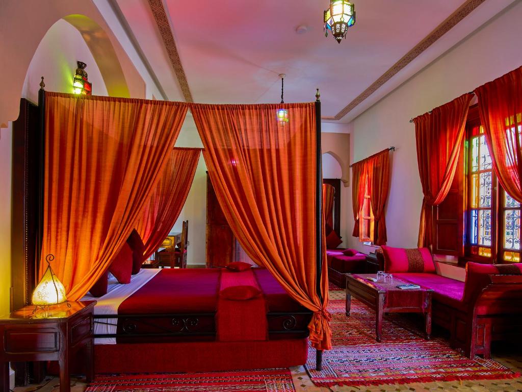 非斯里亚德阿拉姆酒店的一间卧室配有一张带红色窗帘的床和一张沙发