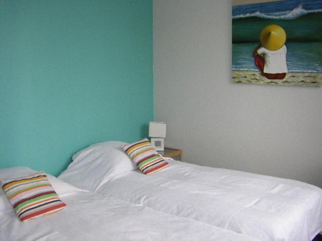 里尔沃邦套房公寓酒店的卧室配有一张白色床,墙上挂有绘画作品