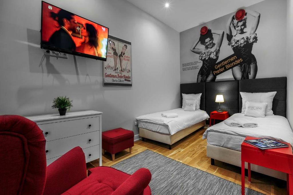 罗兹彼得库夫电影室公寓式酒店的一间卧室设有两张床,墙上配有电视。