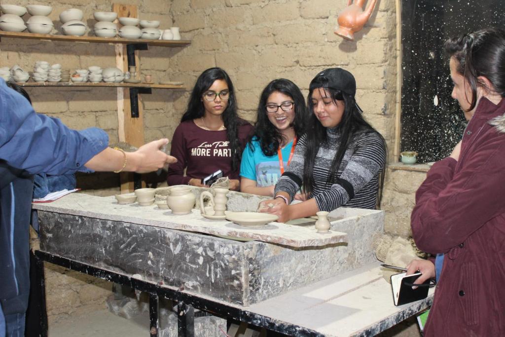 拉基拉Posada El Artesano De Raquira的一群站在餐桌边做陶器的妇女