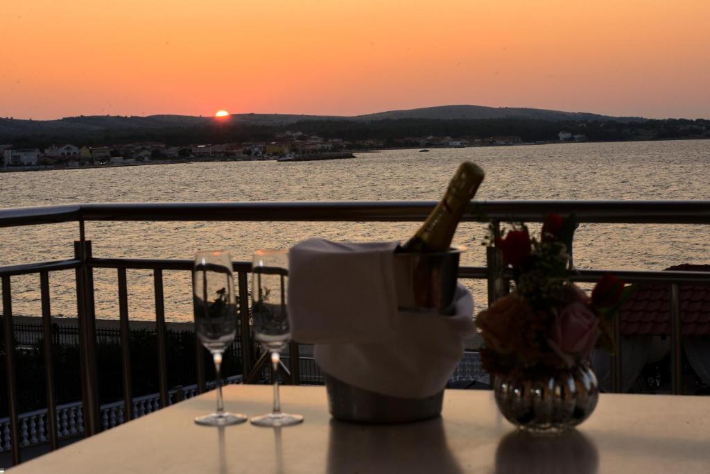 维尔Sunset Deluxe Villa的阳台上的一张桌子和酒杯,享有日落美景