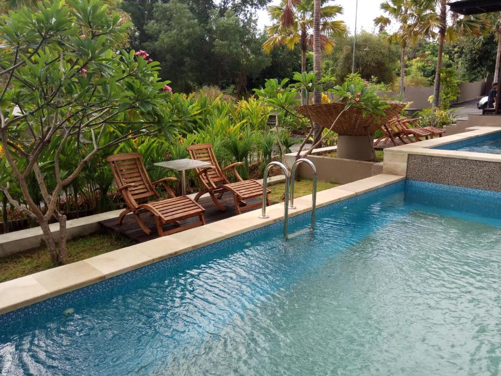图兰奔巴厘乌玛汀君酒店的庭院内一个带椅子和桌子的游泳池