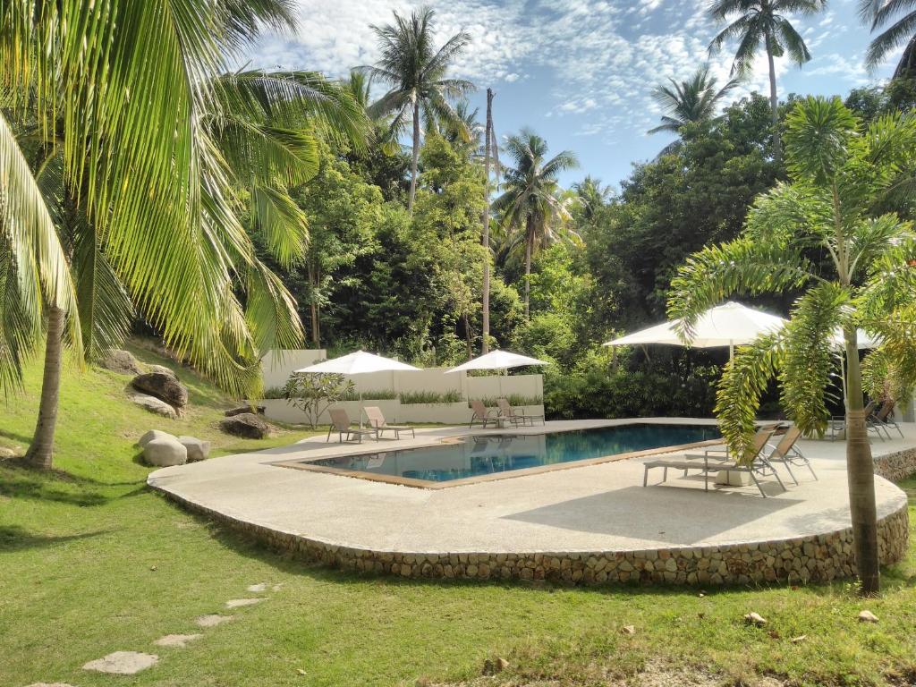 涛岛Woodlawn Villas Resort的庭院内一个带椅子和遮阳伞的游泳池
