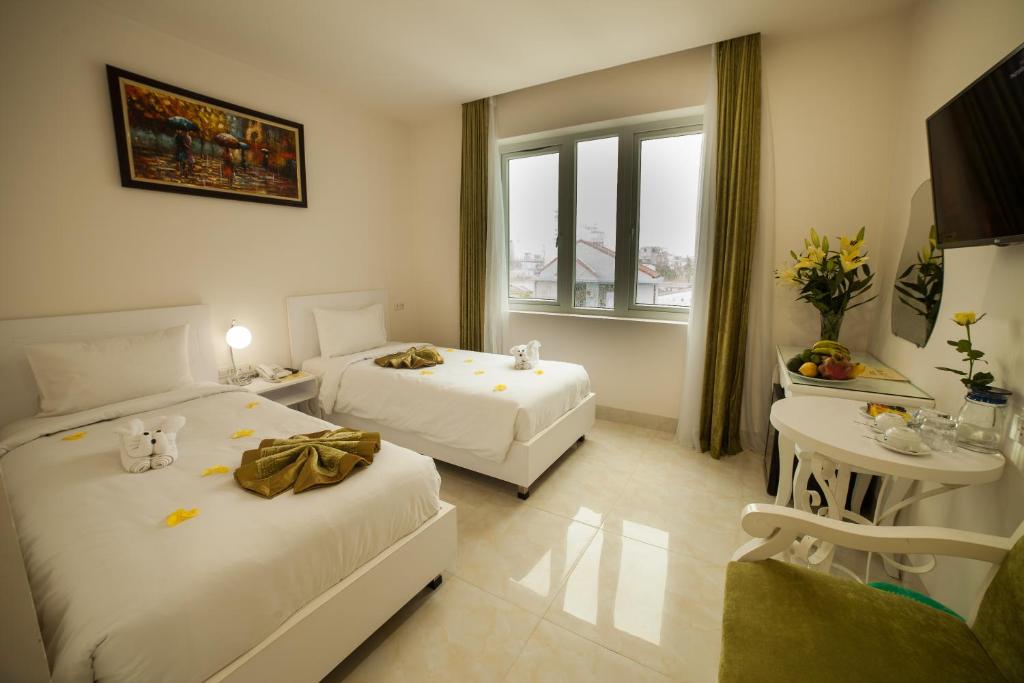 顺化柏勒酒店的酒店客房设有两张床和一张桌子。