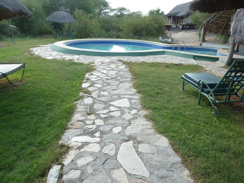 Kwa KuchiniaRoika Tarangire Tented Lodge的通往带长凳的游泳池的石头路径