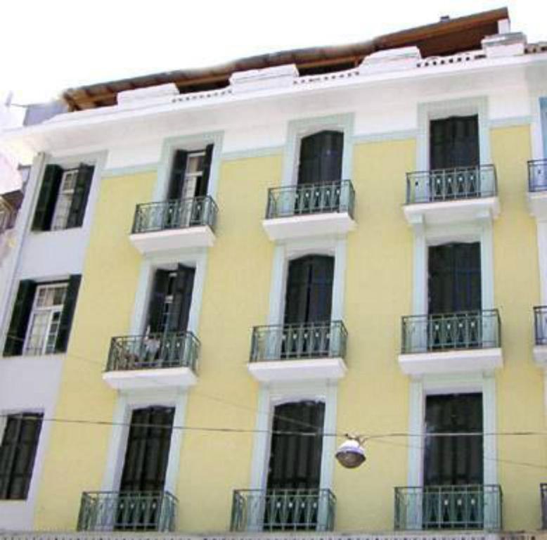 雅典宙斯旅馆的黄色和白色的建筑,设有窗户和阳台