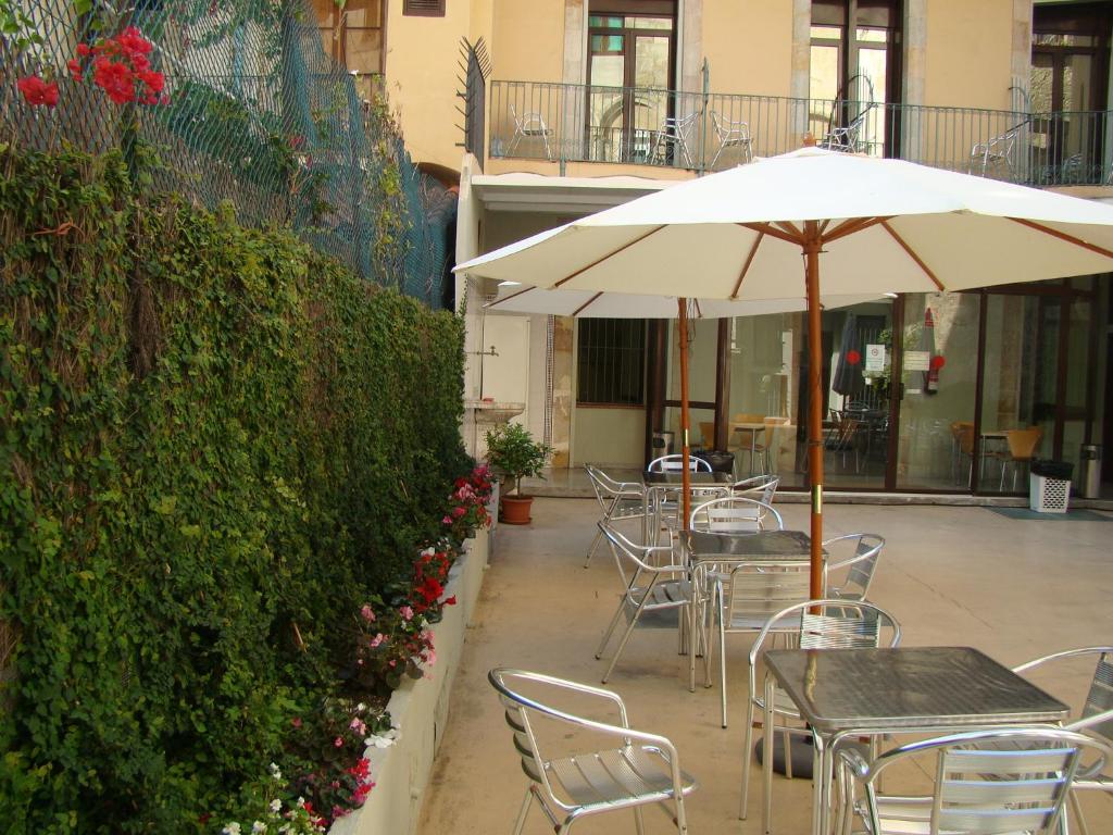 巴塞罗那Hostal La Terrassa的一个带桌椅和遮阳伞的庭院