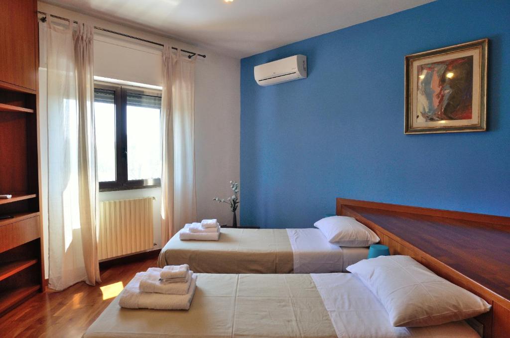巴里Bed and Breakfast La Villa AMBIENTI SANIFICATI CON GENERATORE DI OZONO的一间卧室设有两张床和蓝色的墙壁