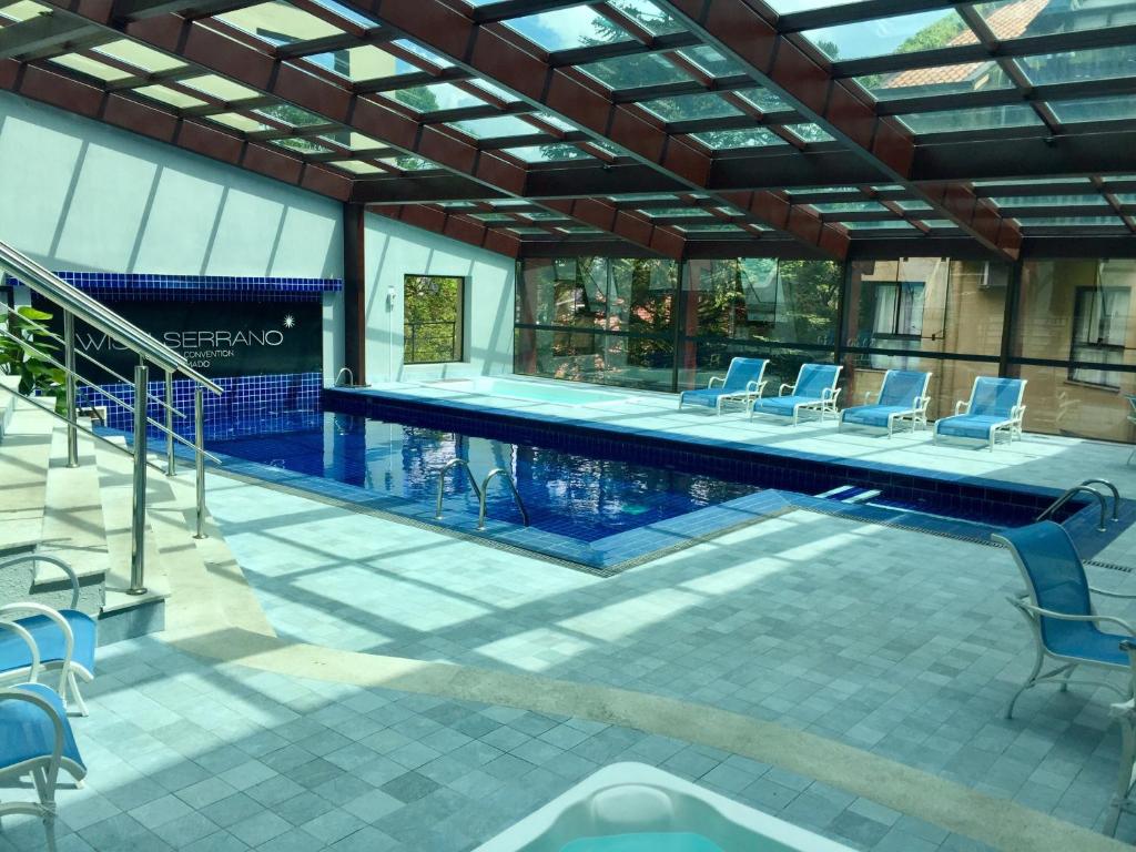 格拉玛多Flat Prodigy Serrano Hotel的一个带蓝色椅子的游泳池和一个游泳池