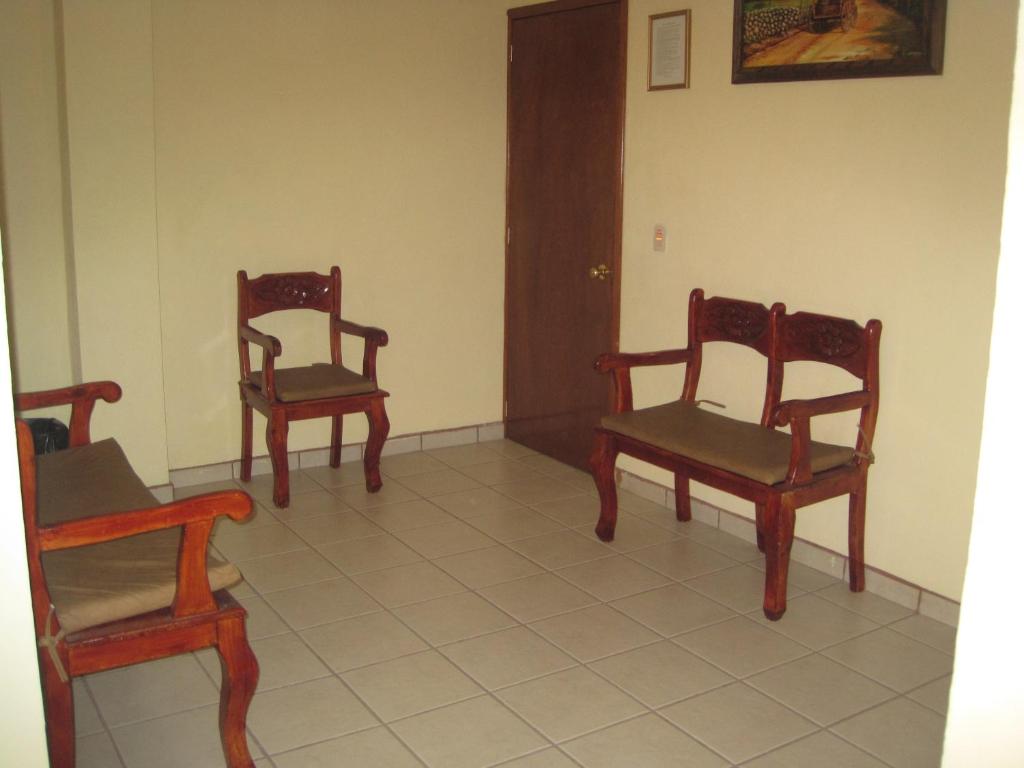 萨卡特卡斯科尔特斯之家酒店的一间房间,铺有瓷砖地板,配有三把椅子