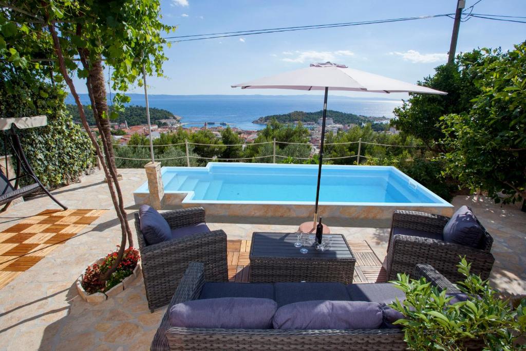 马卡尔斯卡Villa Sukara的一个带椅子和遮阳伞的庭院和一个游泳池